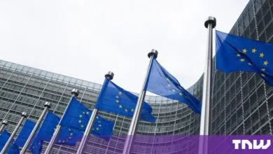 Row of European Union flags waving in front of the Berlaymont building in Brussels.