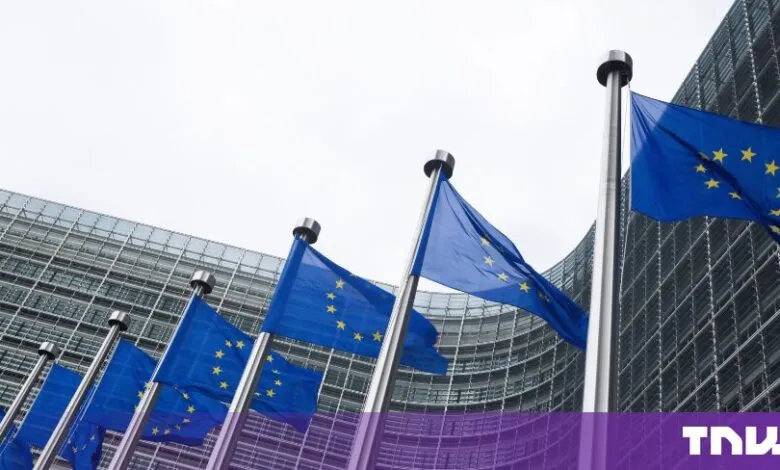 Row of European Union flags waving in front of the Berlaymont building in Brussels.