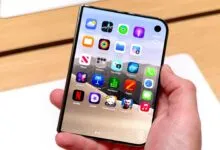 A person holds a foldable smartphone with a flexible OLED display showing colorful app icons.