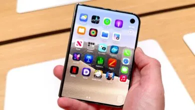 A person holds a foldable smartphone with a flexible OLED display showing colorful app icons.