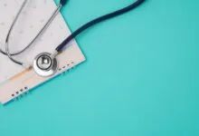 Medical stethoscope resting on a December calendar page against a turquoise background