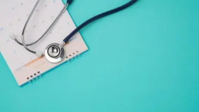 Medical stethoscope resting on a December calendar page against a turquoise background