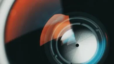 Close-up of a camera lens aperture blades with orange and blue light reflections