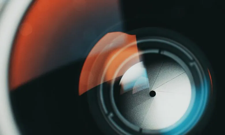 Close-up of a camera lens aperture blades with orange and blue light reflections