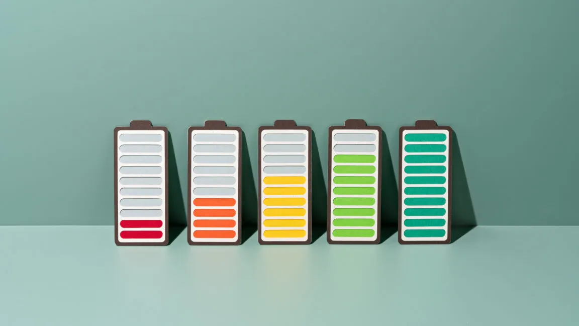 Five paper craft batteries showing progressive charging levels from empty to full against a green backdrop.