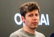 Close-up portrait of OpenAI CEO Sam Altman wearing a gray sweater against a dark background