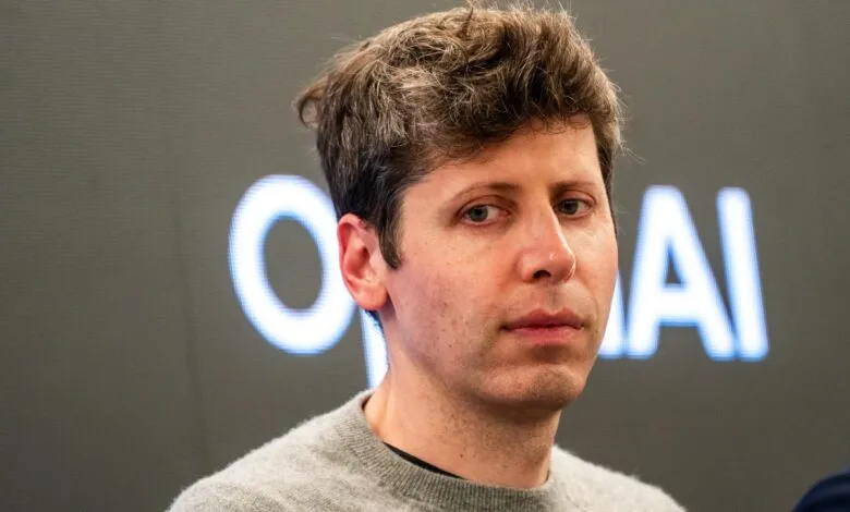 Close-up portrait of OpenAI CEO Sam Altman wearing a gray sweater against a dark background