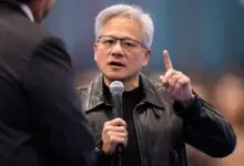 NVIDIA CEO Jensen Huang speaks into a microphone while raising a finger in discussion.