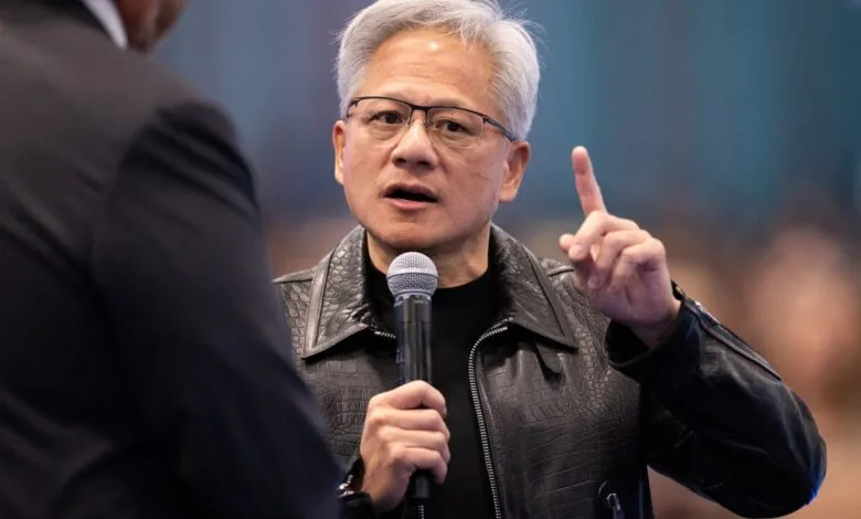 NVIDIA CEO Jensen Huang speaks into a microphone while raising a finger in discussion.