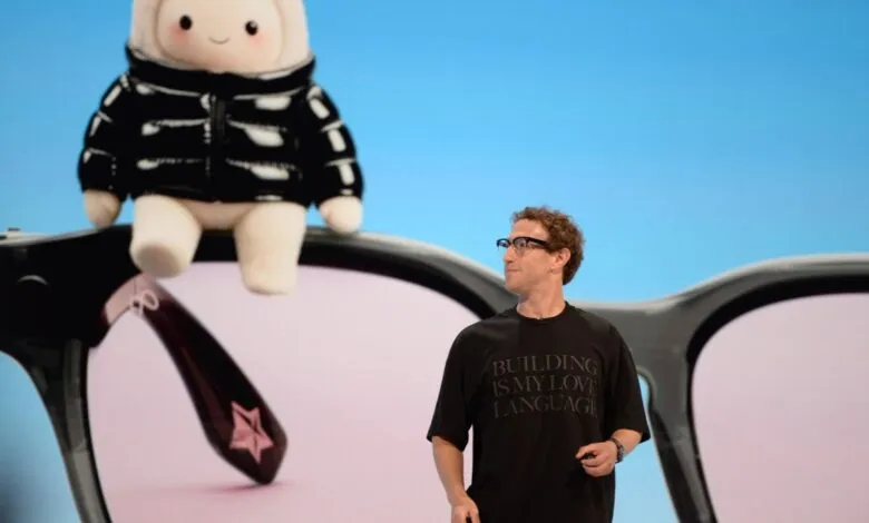 Meta CEO Mark Zuckerberg presents on stage in front of a giant graphic of smart glasses and a plush toy.