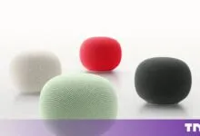 Four Google Home Mini smart speakers in white, green, red, and dark grey arranged on a white surface.
