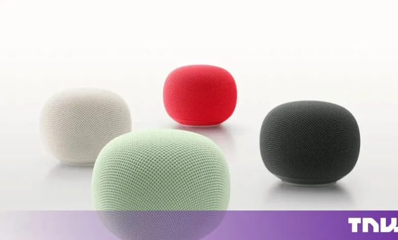 Four Google Home Mini smart speakers in white, green, red, and dark grey arranged on a white surface.