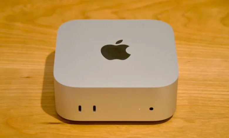 Silver Apple Mac mini desktop computer resting on a warm wooden surface.