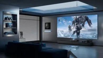 Futuristic home theater gaming room featuring a massive screen, blue couch, and modern decor.