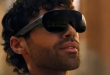 Close-up of a man wearing sleek black Meta VR glasses with reflective lenses outdoors at sunset.