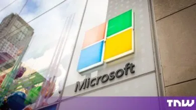 The Microsoft logo mounted on a glass storefront facade outdoors.
