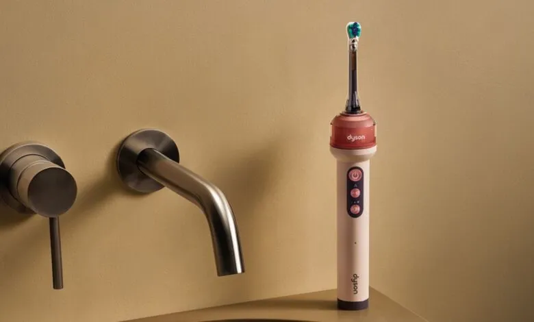 Modern Dyson electric toothbrush standing next to a contemporary wall-mounted faucet on a beige sink