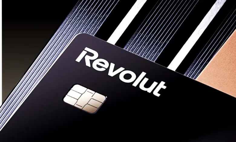 Close-up of a black Revolut debit card with white branding and a gold EMV chip.