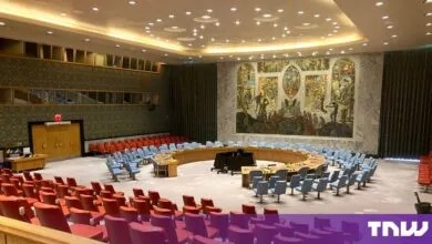 Empty United Nations Security Council Chamber featuring a horseshoe-shaped table and large mural.