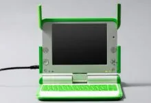 Bright green and silver XO laptop by One Laptop per Child on a plain gray surface
