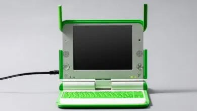 Bright green and silver XO laptop by One Laptop per Child on a plain gray surface