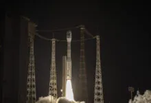 Vega-C rocket launching at night, surrounded by lightning protection towers