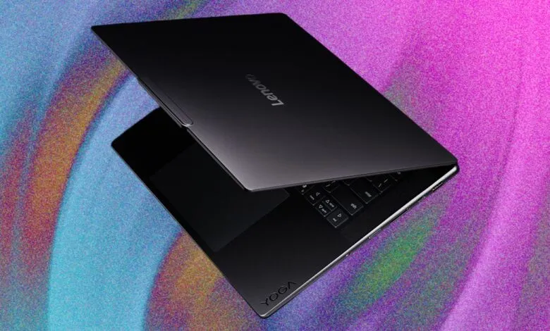 Sleek black Lenovo Yoga laptop angled against a vibrant pink and blue textured background.