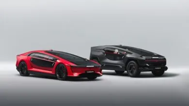 Two futuristic electric concept cars, one red and one black, parked side by side on a light gray background.