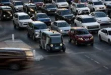 Zoox robotaxi navigating bustling Las Vegas traffic alongside traditional cars.