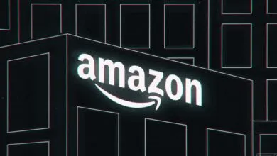 Illuminated Amazon logo on a building with a cyan and red chromatic aberration effect.