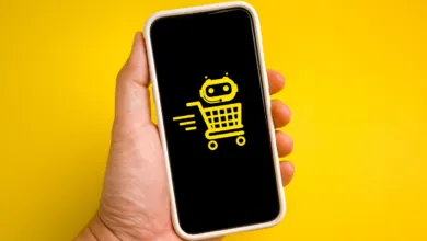 Hand holding a smartphone displaying a yellow AI shopping cart icon on a black screen.