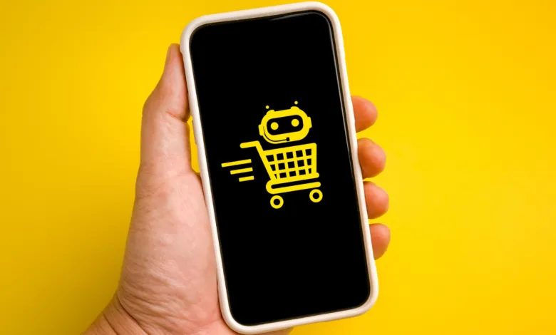 Hand holding a smartphone displaying a yellow AI shopping cart icon on a black screen.