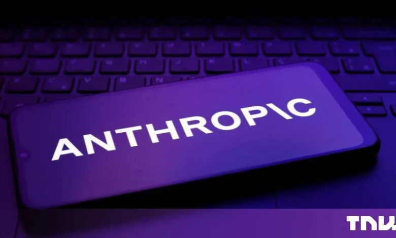 A smartphone displaying the Anthropic logo resting on a backlit computer keyboard.