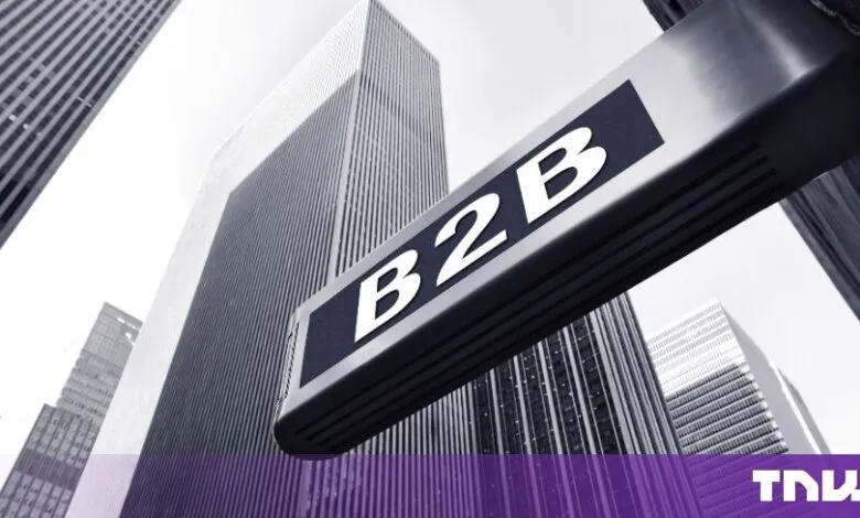 A close-up of a B2B sign against a background of towering skyscrapers.