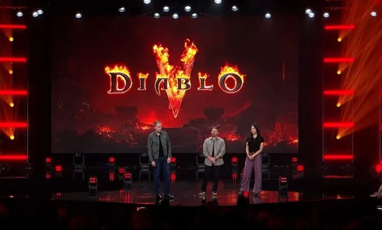 Three presenters stand on a dark stage before a glowing Diablo game logo screen.
