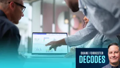 Duane Forrester decodes future trends as colleagues analyze data on a laptop in a modern office meeting.