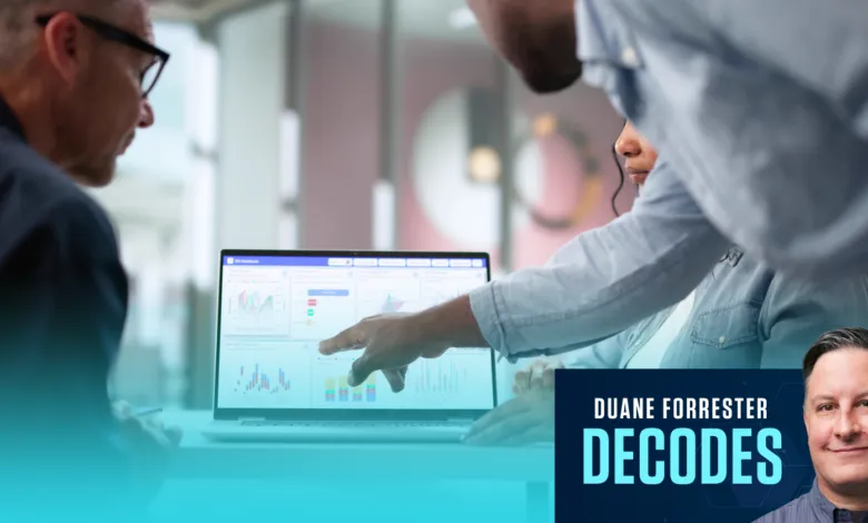 Duane Forrester decodes future trends as colleagues analyze data on a laptop in a modern office meeting.