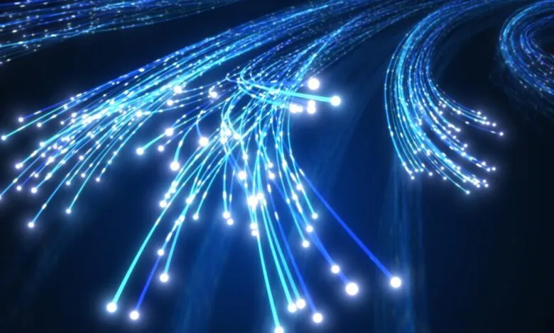 Glowing blue fiber optic cables transmitting high-speed data across a dark background.