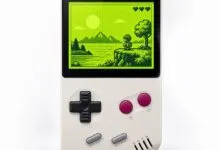 Close-up of a retro handheld gaming console displaying a pixelated landscape on a green screen.