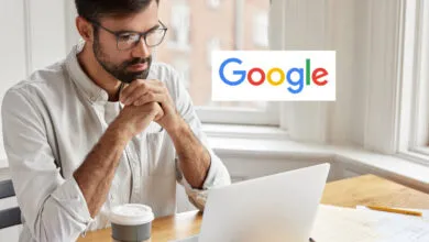 Man wearing glasses looks thoughtfully at a laptop next to the Google logo.