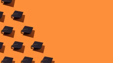 Pattern of black graduation caps with gold tassels arranged on a vibrant orange background.
