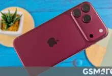 Deep red iPhone resting diagonally on a bright blue wooden surface with decorative coasters.