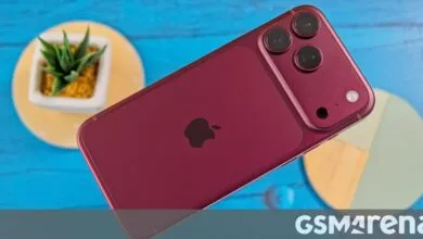 Deep red iPhone resting diagonally on a bright blue wooden surface with decorative coasters.