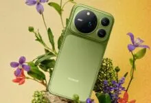 Olive green Honor smartphone resting among purple flowers against a warm textured background