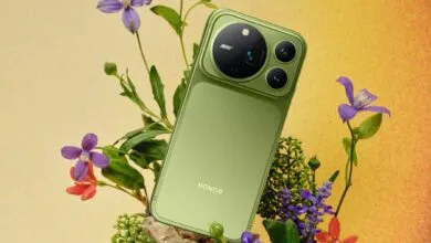Olive green Honor smartphone resting among purple flowers against a warm textured background