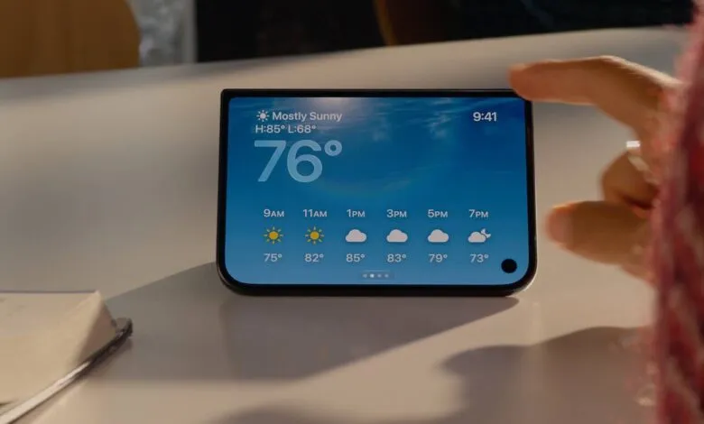 A hand interacts with a smartphone displaying a detailed weather app interface on a white table.