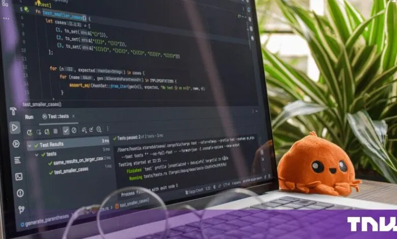 Laptop screen displaying Rust code in an editor with a successful test results panel and cute orange Ferris mascot.