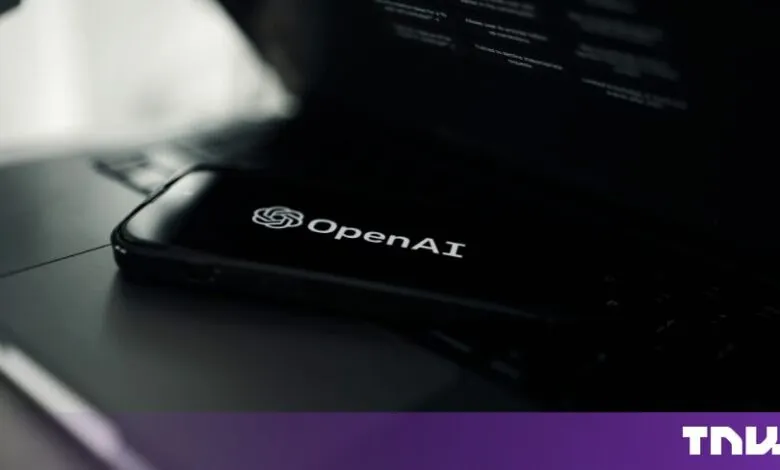 Smartphone displaying the OpenAI logo resting on a laptop keyboard