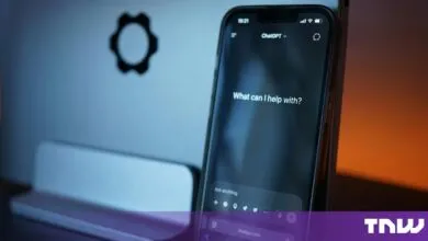 Smartphone displaying the ChatGPT app interface against a blurred laptop background.