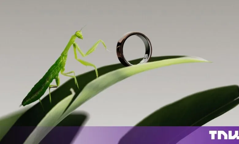 A vibrant green praying mantis examines a smart ring resting on a leaf against a neutral background.